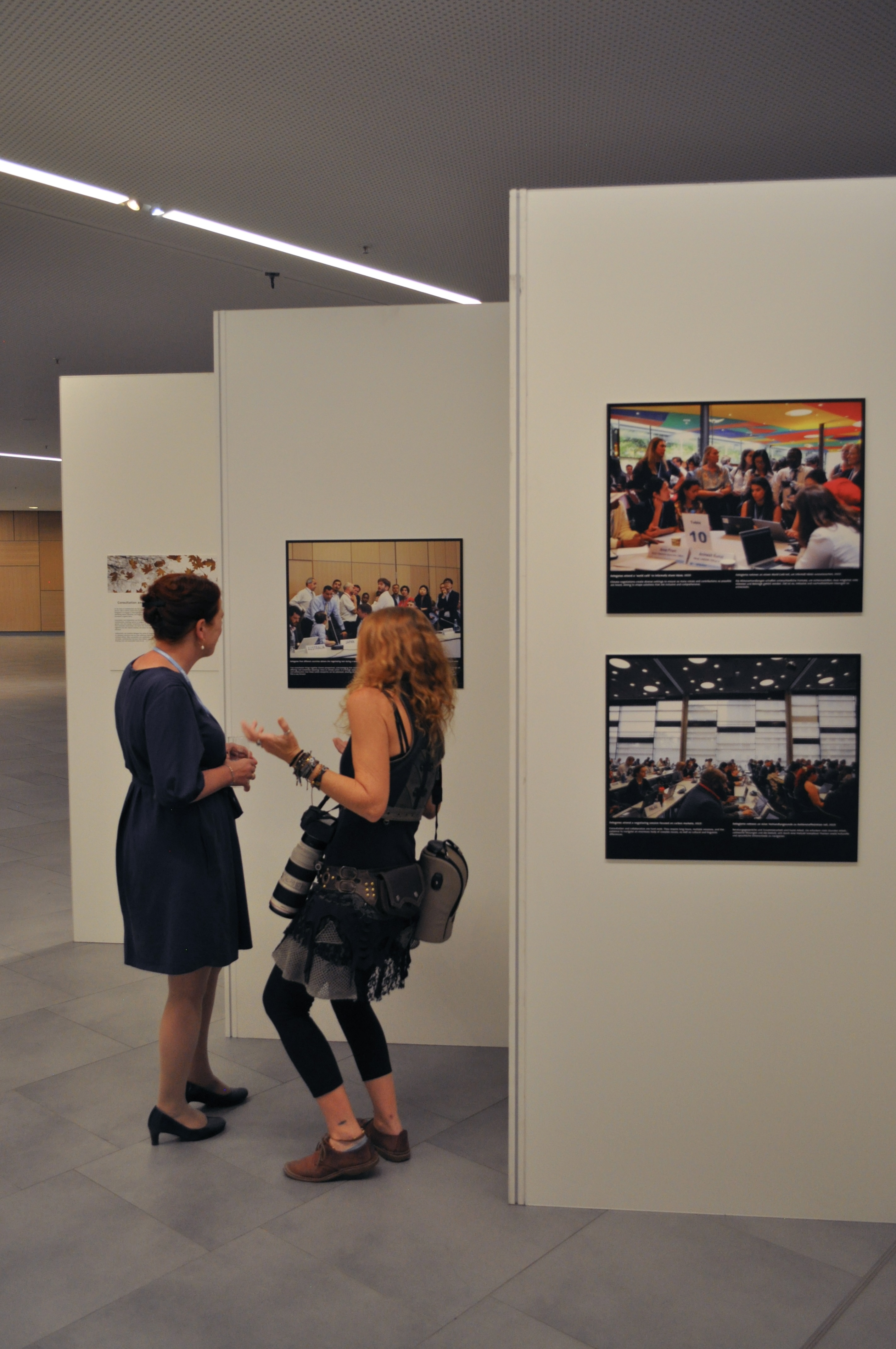 [10] Kiara Worth (right), the UNFCCC’s official photographer, presents a collection of photographs from decades of COPs to Katja Dörner, the mayor of Bonn (left). As the official UNFCCC photographer, Worth seeks to capture the "human side" of climate negotiations. She titled her exhibition "Finding Common Ground," describing it as a "love letter to multilateralism." 