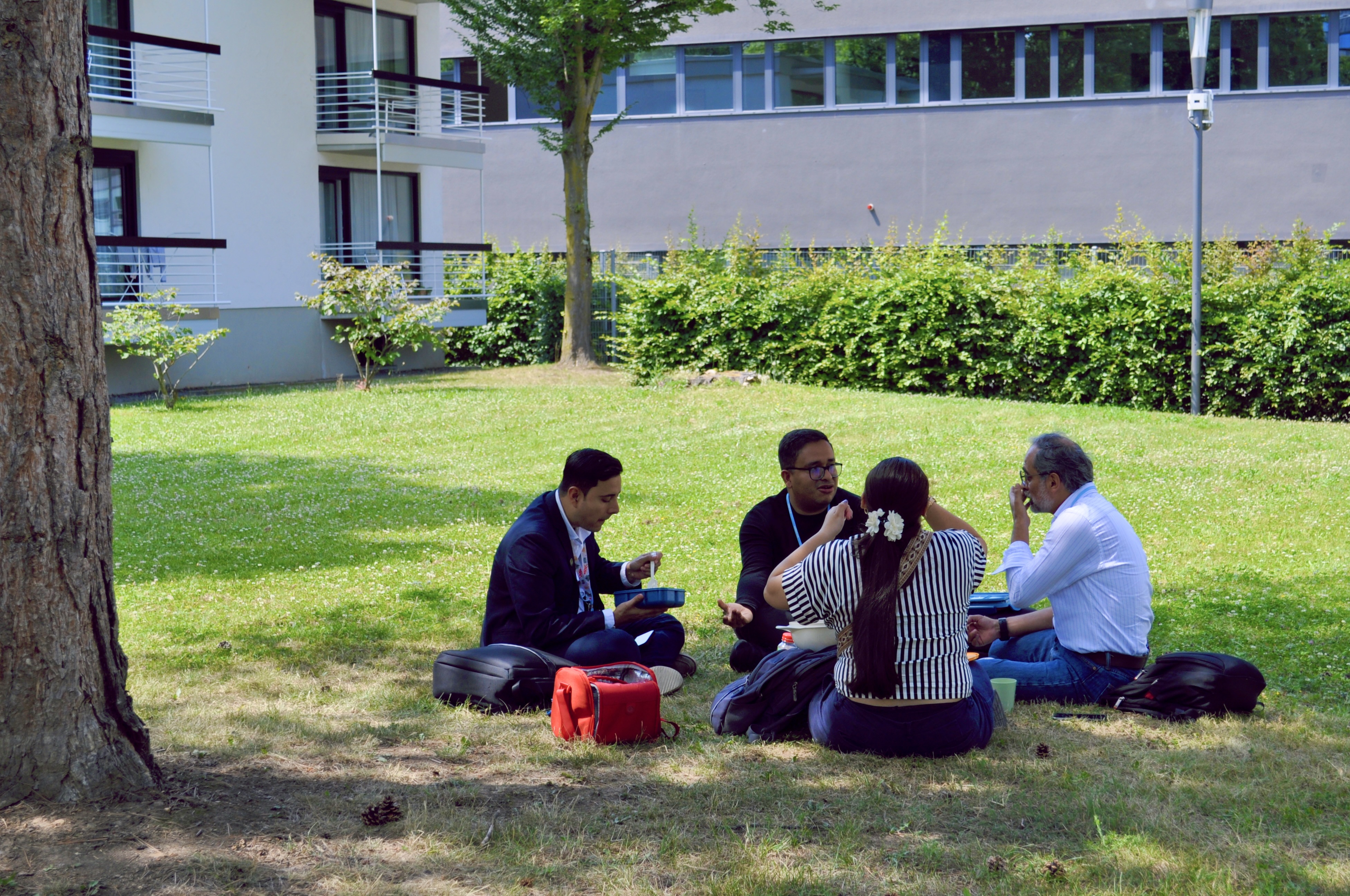 [11] In the early afternoon, delegates take lunch on a shady patch of grass outside the UN complex. 