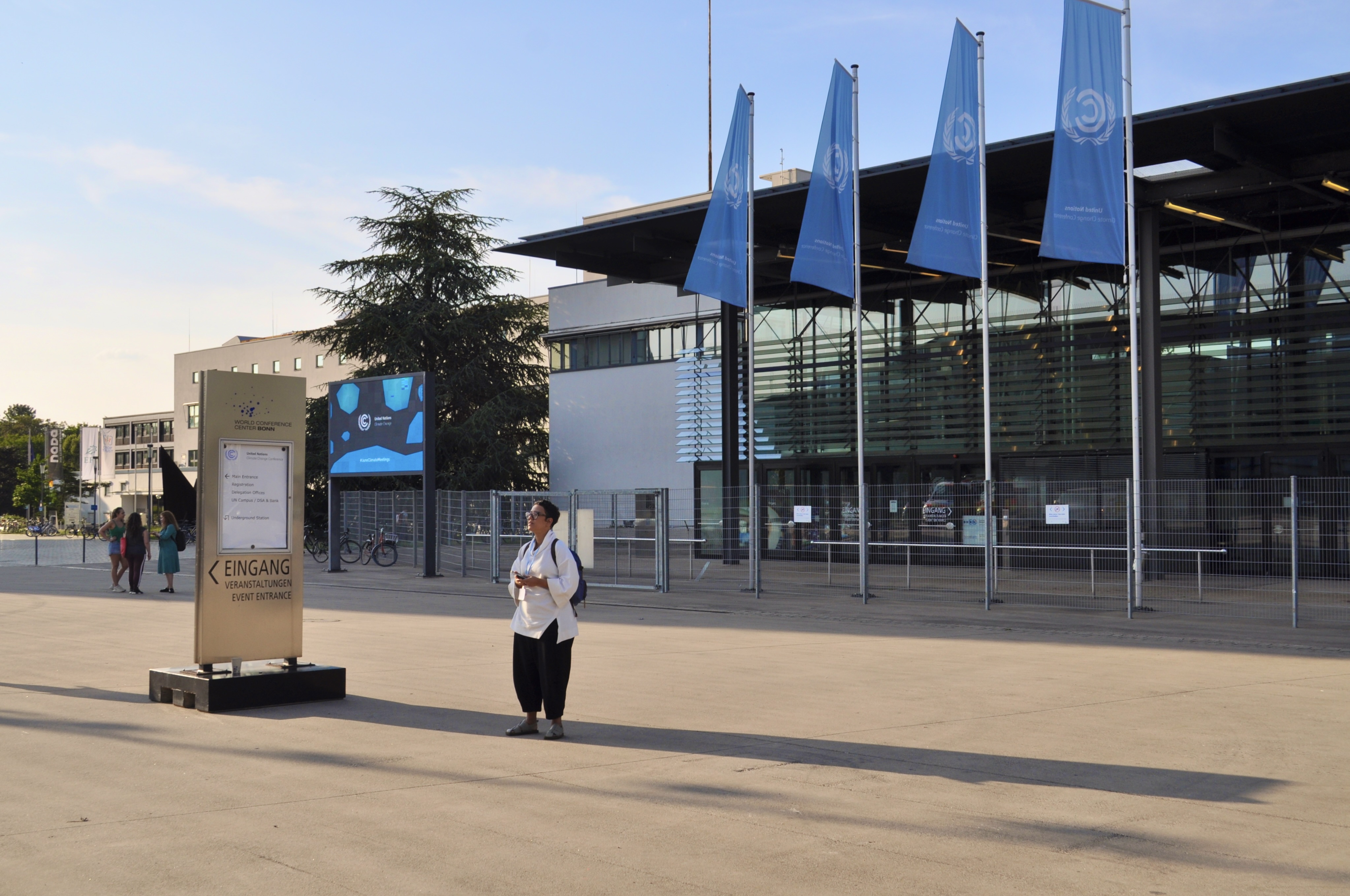 [17] Outside the conference center, a woman shelters from the hot afternoon sun. Though this space filled up during protests, such as the Just Transition Rising Picket-nic, the space emptied out when there were no demonstrations. 