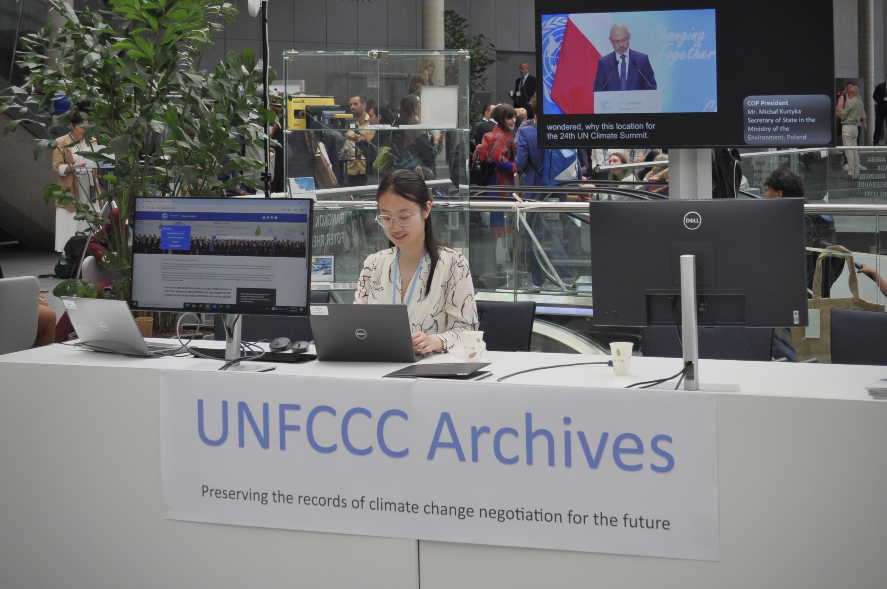 [4] As part of her work for the UNFCCC Archives, Zilin Ye promotes the Archives as a resource for journalists, scholars, diplomats, and the public. Her booth, located in the main atrium of the conference center, showcases the Archives' meeting recordings, digitized transcripts, and photos, as well as memorabilia from past COPs.  